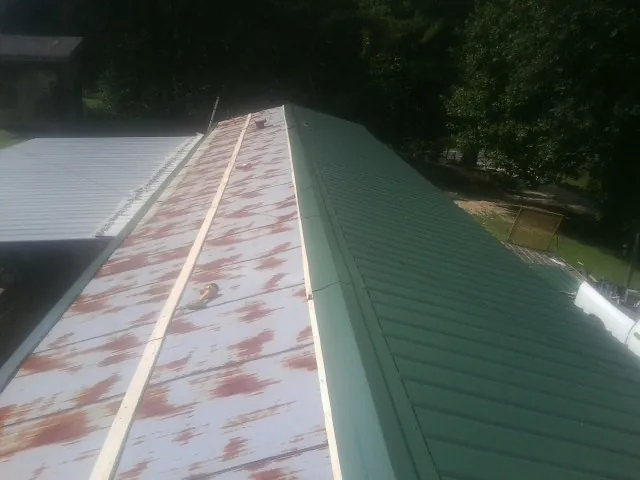 Old rusted panels beside newly installed green metal roofing — Wind Damage Roof Repair by Roofing Brothers in Neversink