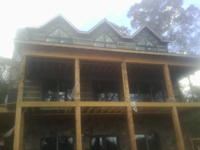 Dormers and porch framing on a large log home under construction — Roof Coating work by our crew in Neversink