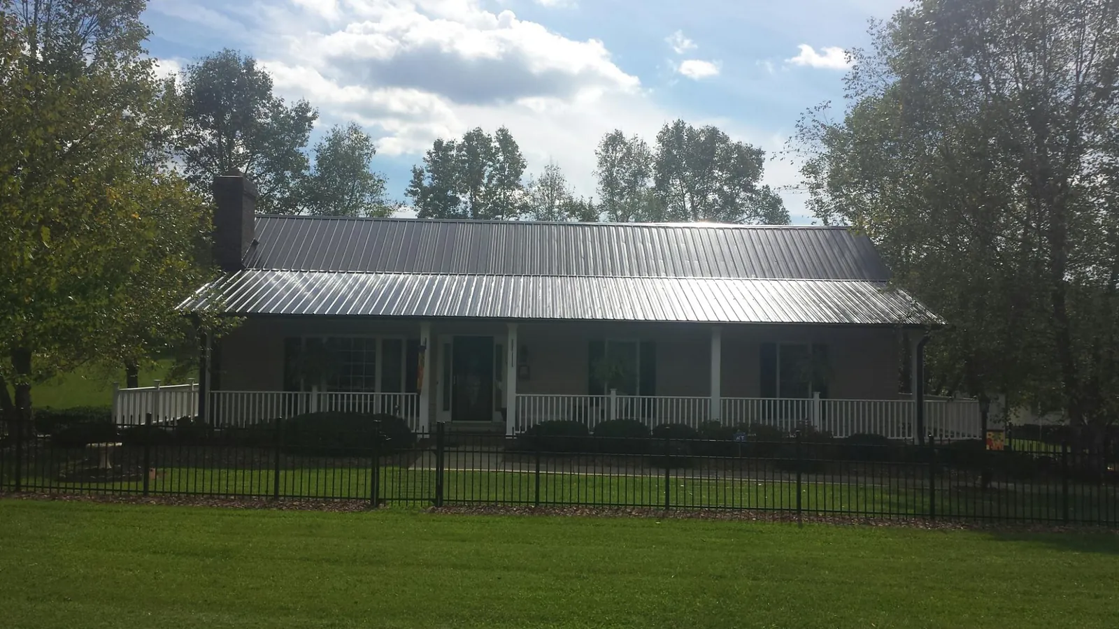 Gray metal roof on a brick ranch with a full width front porch — Gutter Guard Installation work by our crew in Neversink