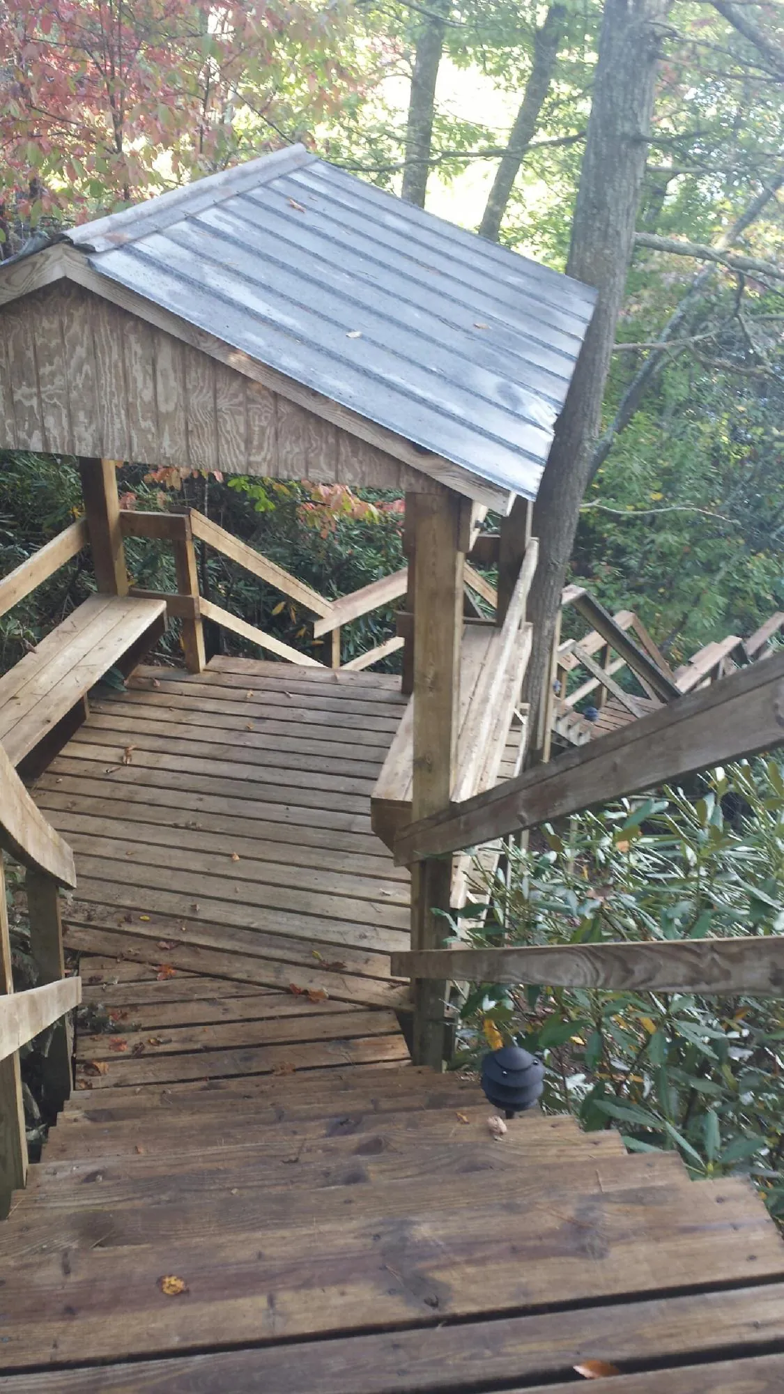 Metal roofed shelter over wooden steps on a wooded walkway — Skylight Repair & Installation work by our crew in Neversink