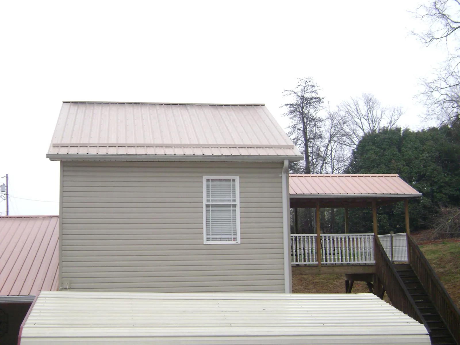 Tan metal roofs on a two story addition and attached porch, from a Roof Replacement job in Neversink
