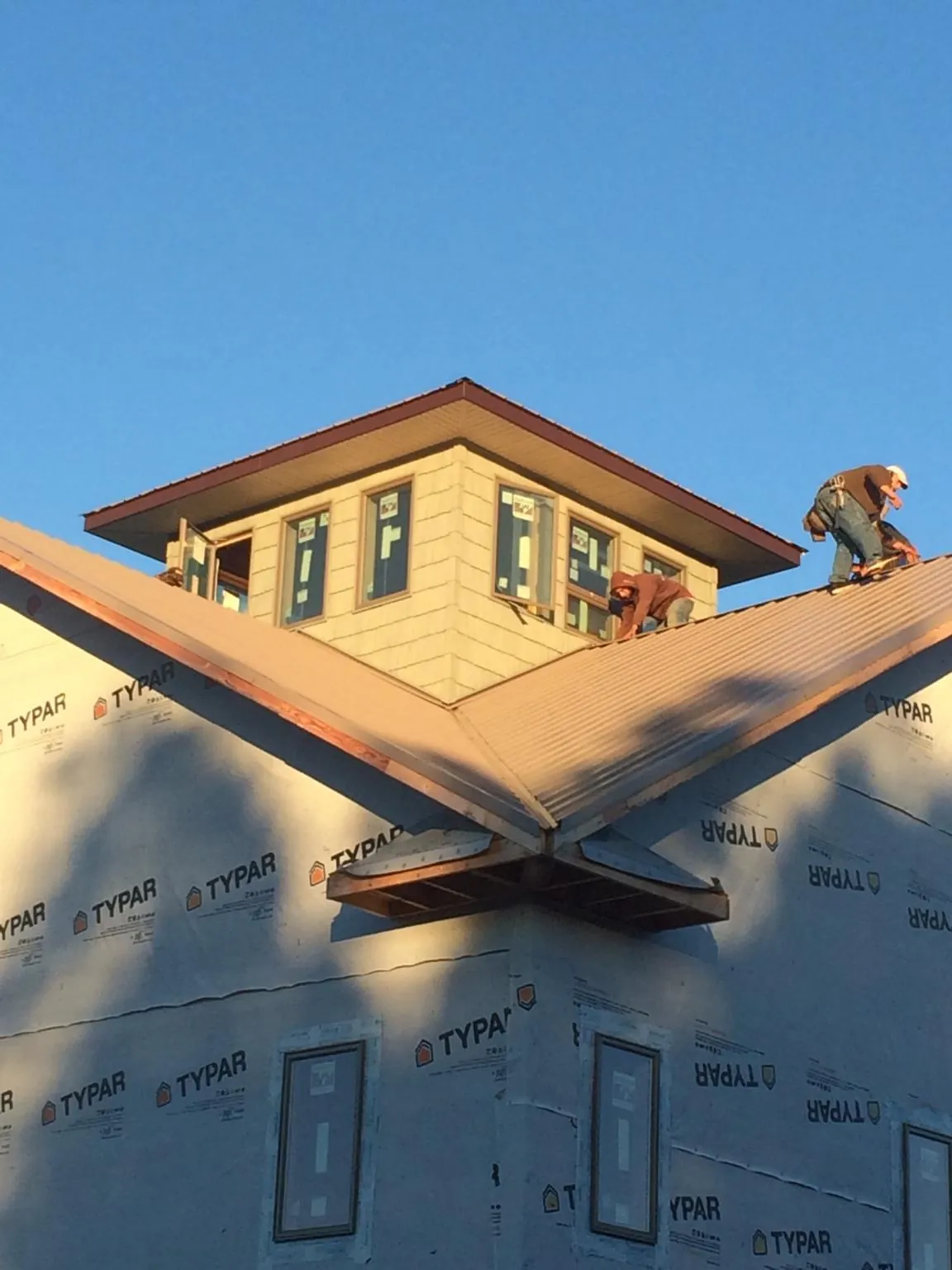 Roofers working around a rooftop cupola on a new metal roof at sunset — Roof Waterproofing in Neversink by Roofing Brothers